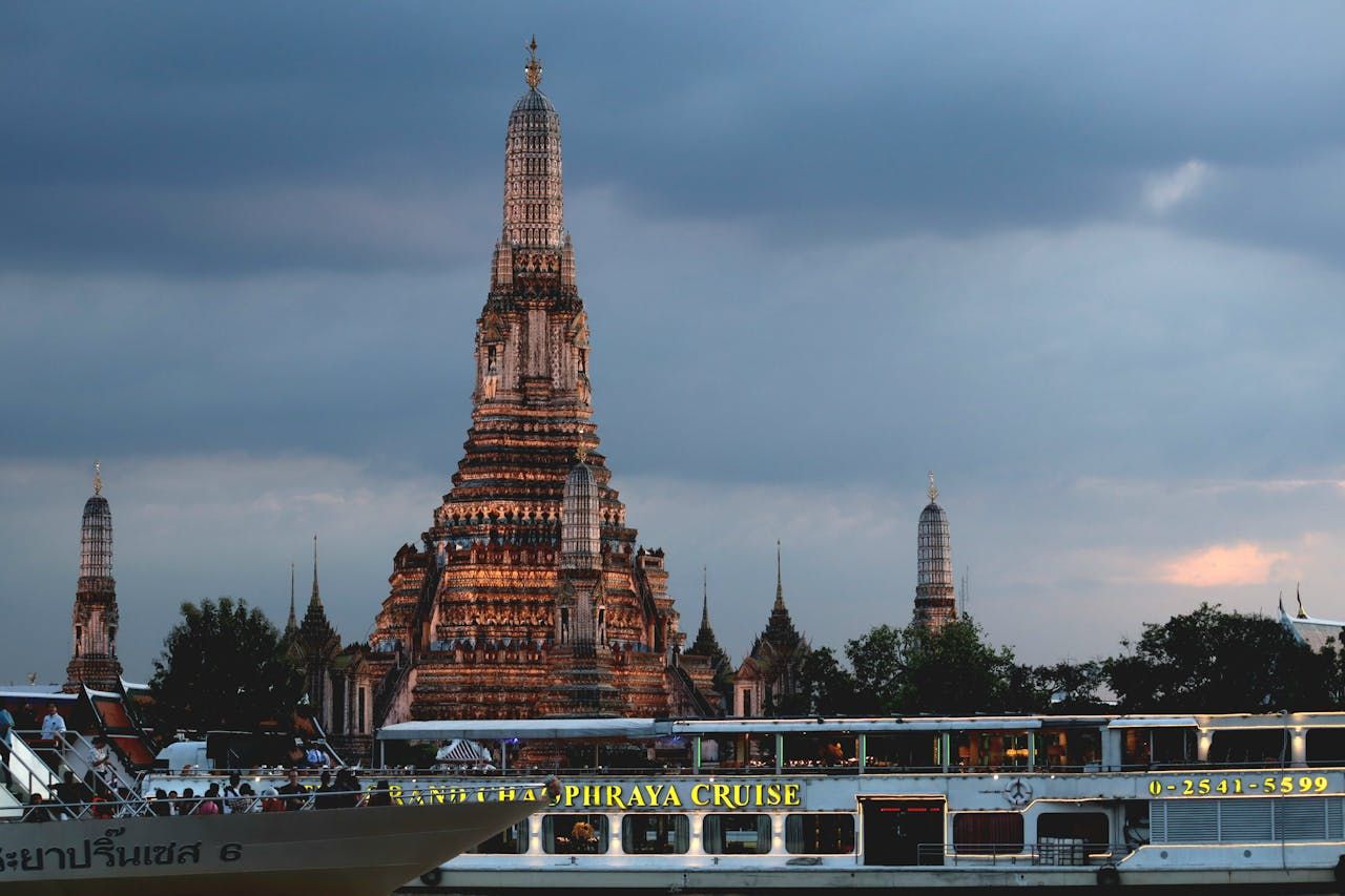 cruise boat on Chao Phraya River at sunset in Bangkok with stunning view of Wat Arun temple